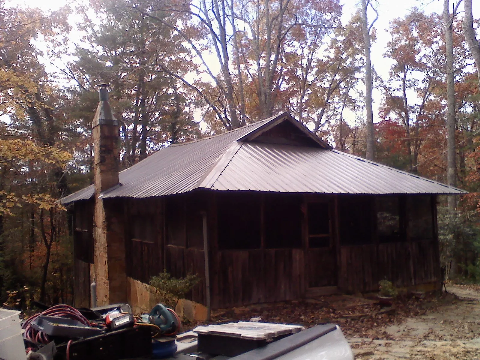 Brown metal hip roof on an old cabin with a stone chimney in Middleton